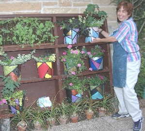 Picture of a lady standing by a set of sheves full of plants